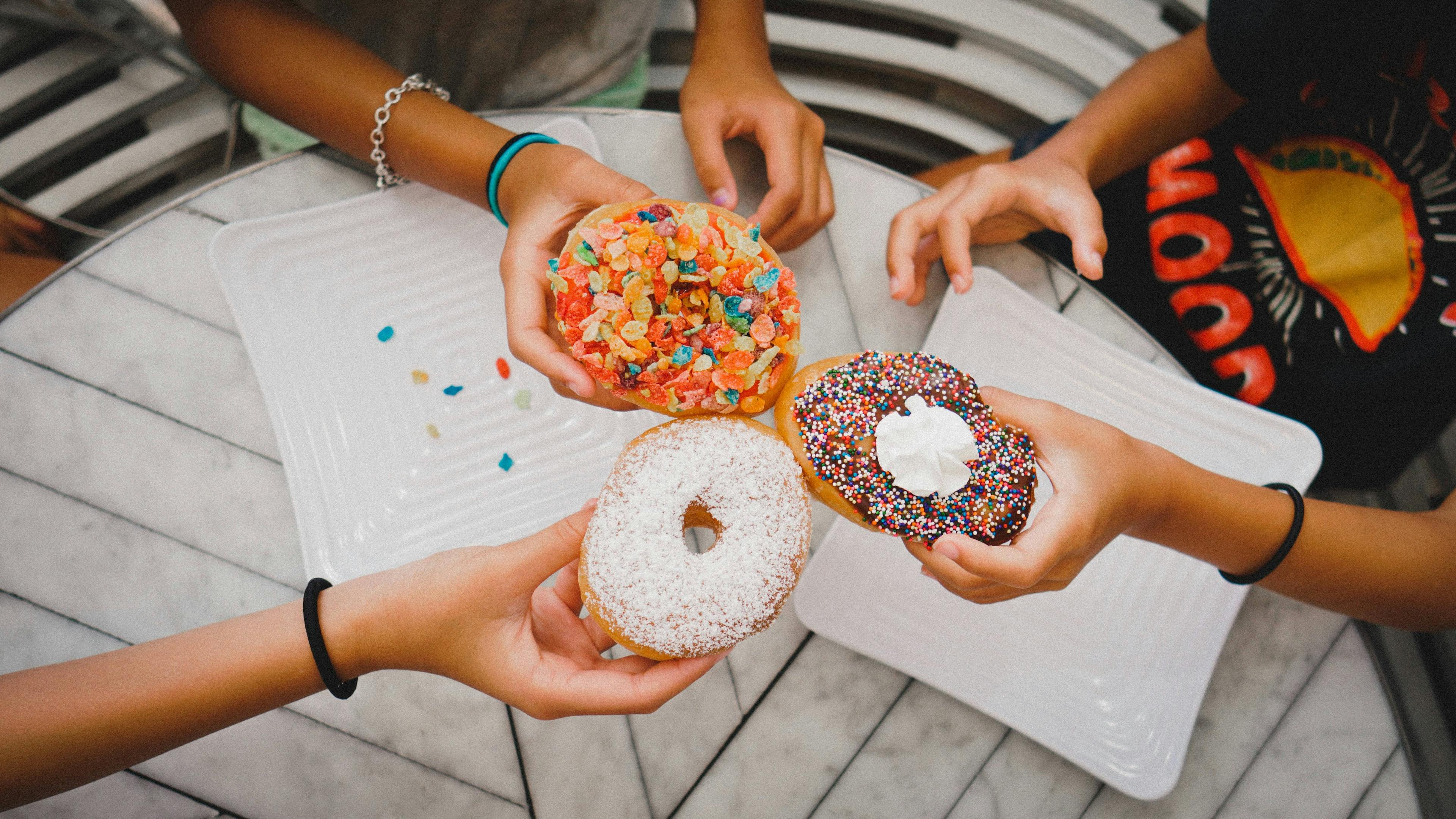 Three people holding donuts