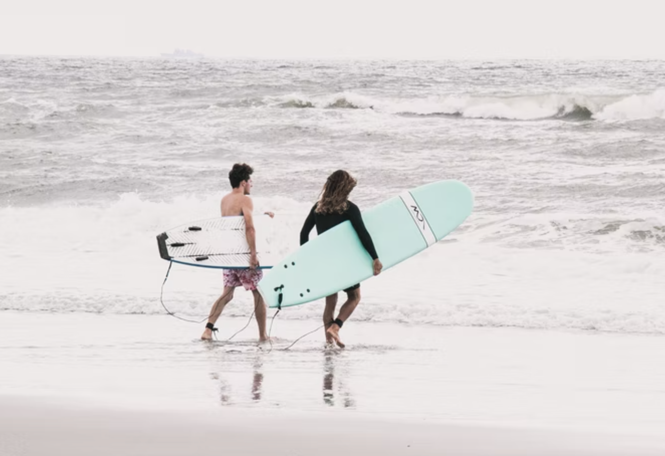 two people going out to surf